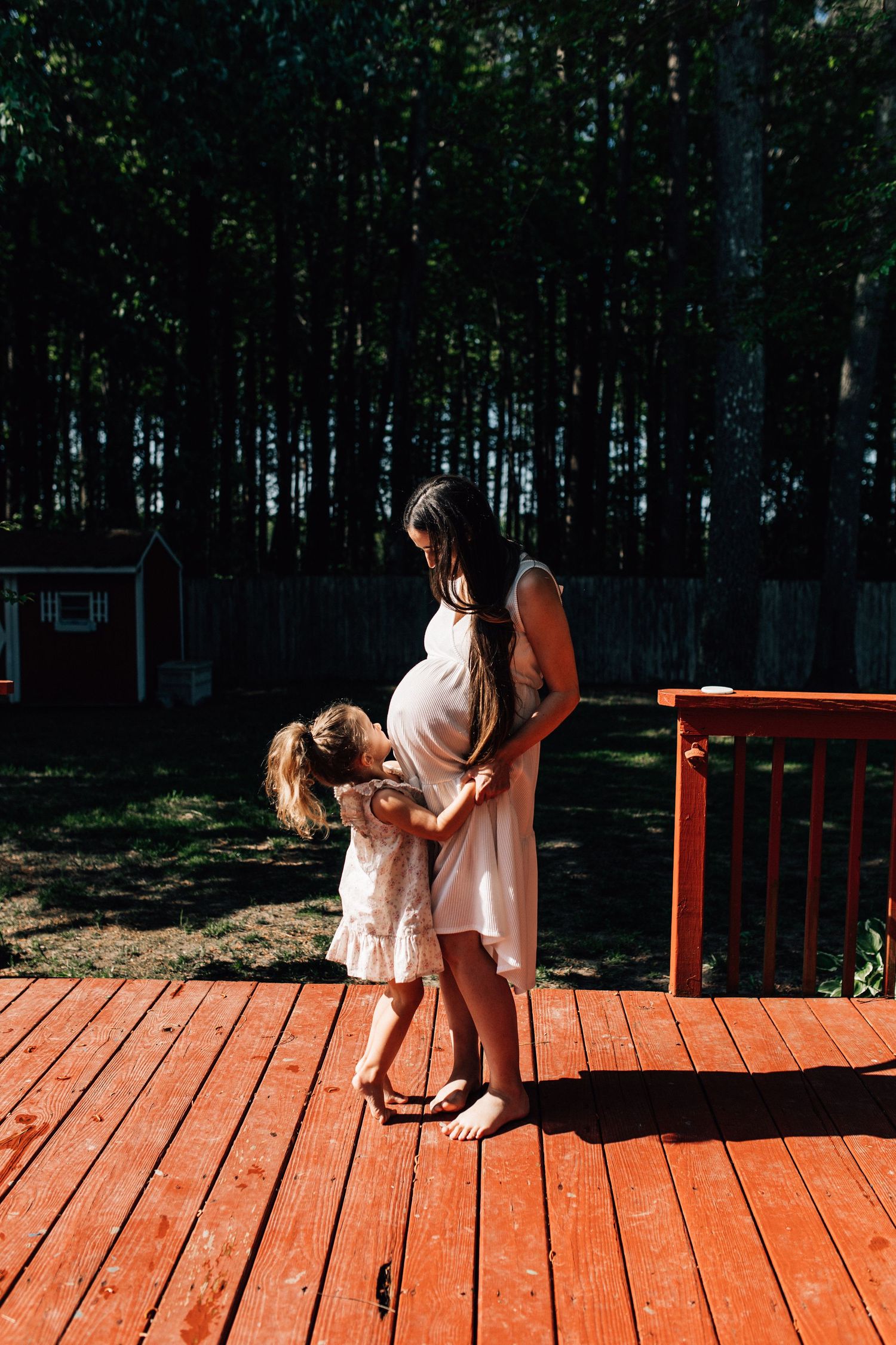 pregnant woman holding child's hands as she labors on the back deck in chesapeake in home maternity session