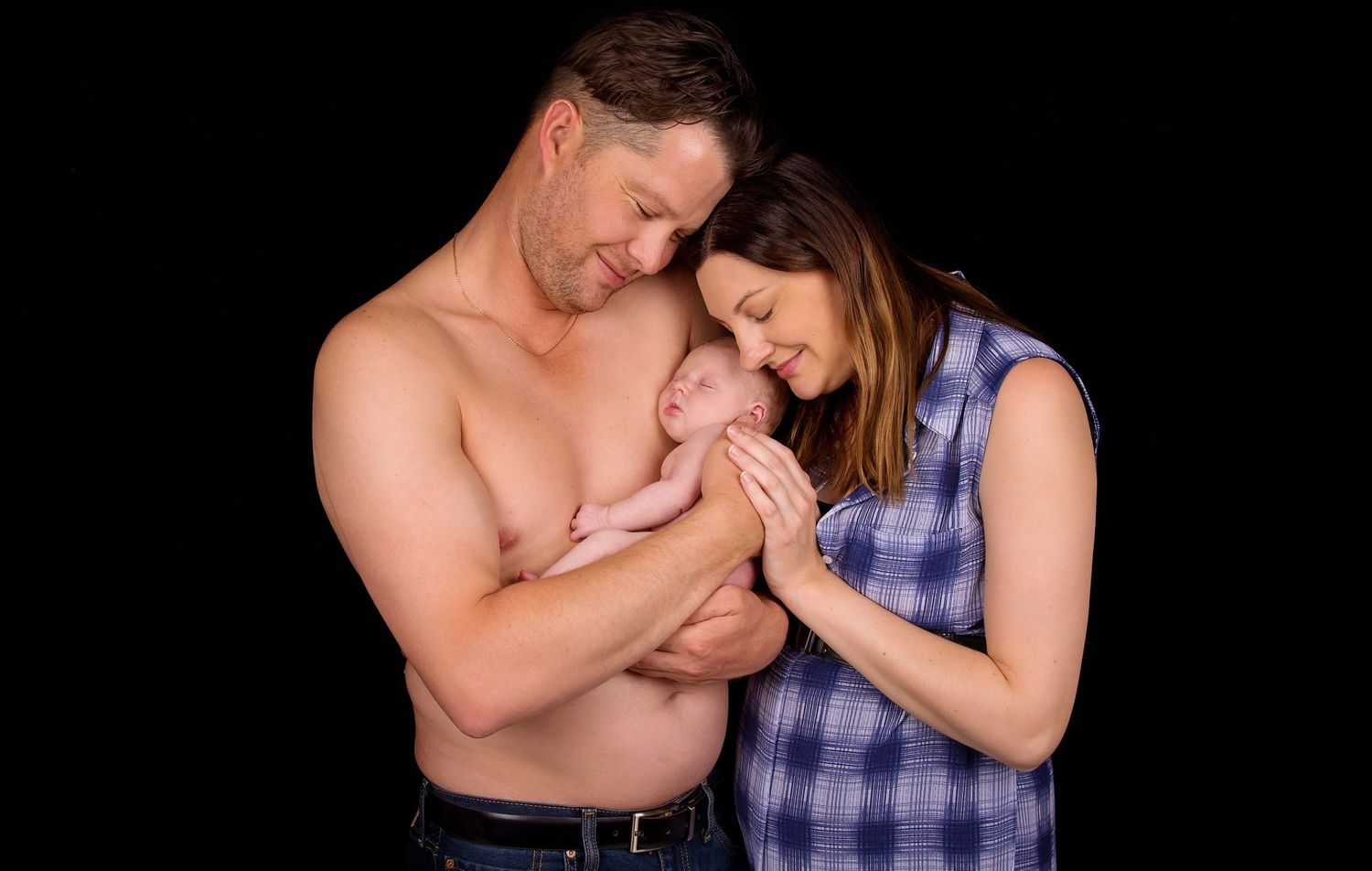 mother and father holding newborn baby lovingly