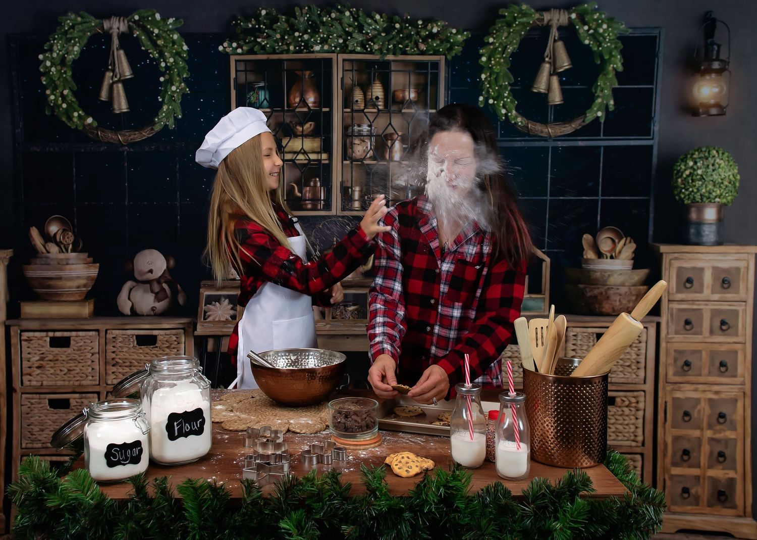 Cozy Christmas themed photo setup with greenery, vintage furniture, and warm lighting.