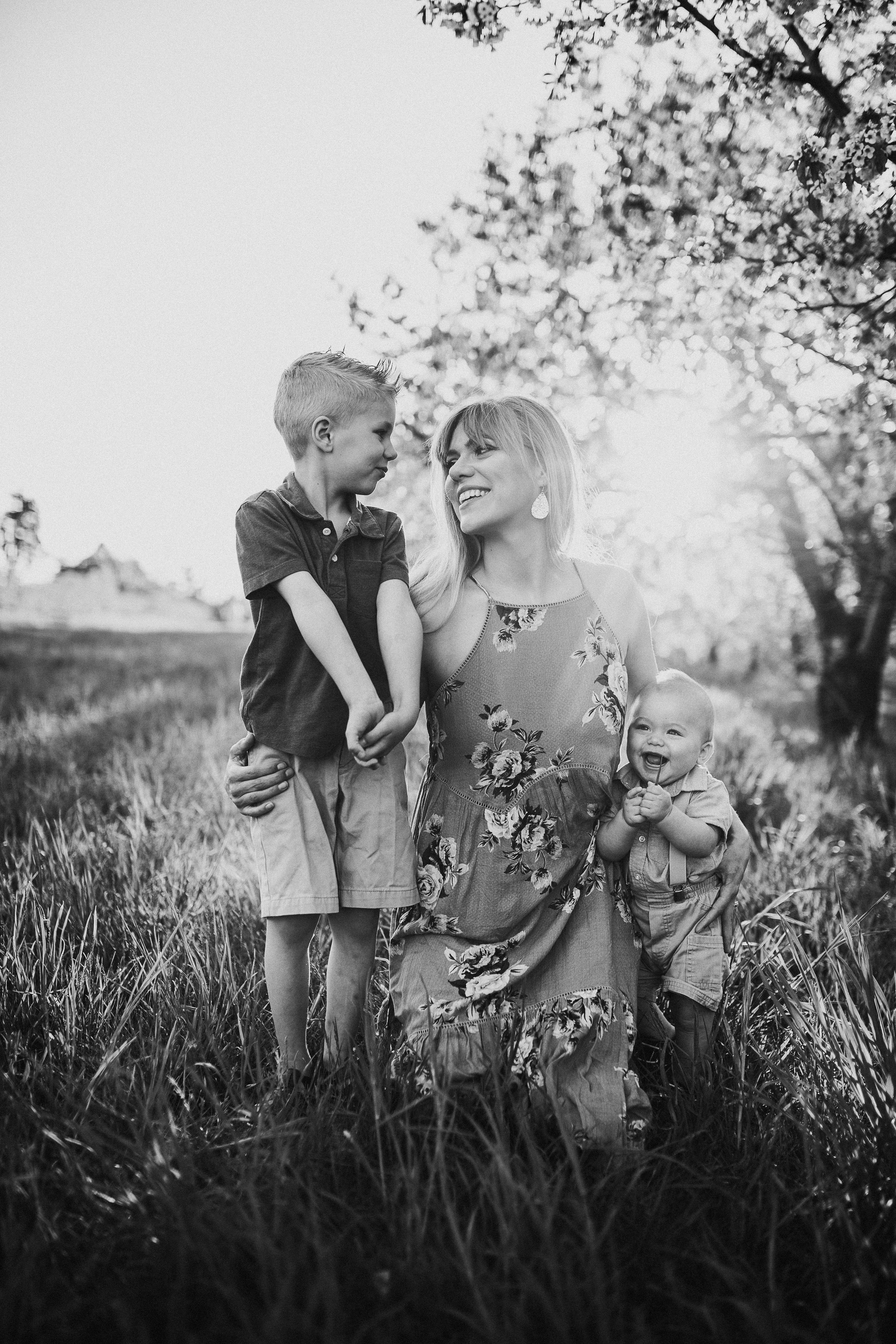 Family shares tender moment together in tall grass during golden hour.
