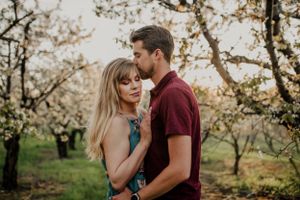 Romantic couple embracing in a blooming spring orchard during golden hour.