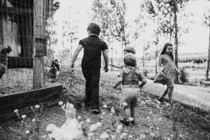 Children stand in a garden looking through a fence in this black and white countryside scene.