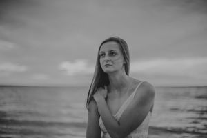 Dramatic black and white portrait of figure against ocean horizon.