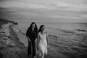 Two figures walking along beach shoreline in black and white.