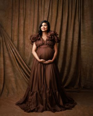 Romantic maternity photo in chocolate brown flowing gown with ruffle details.