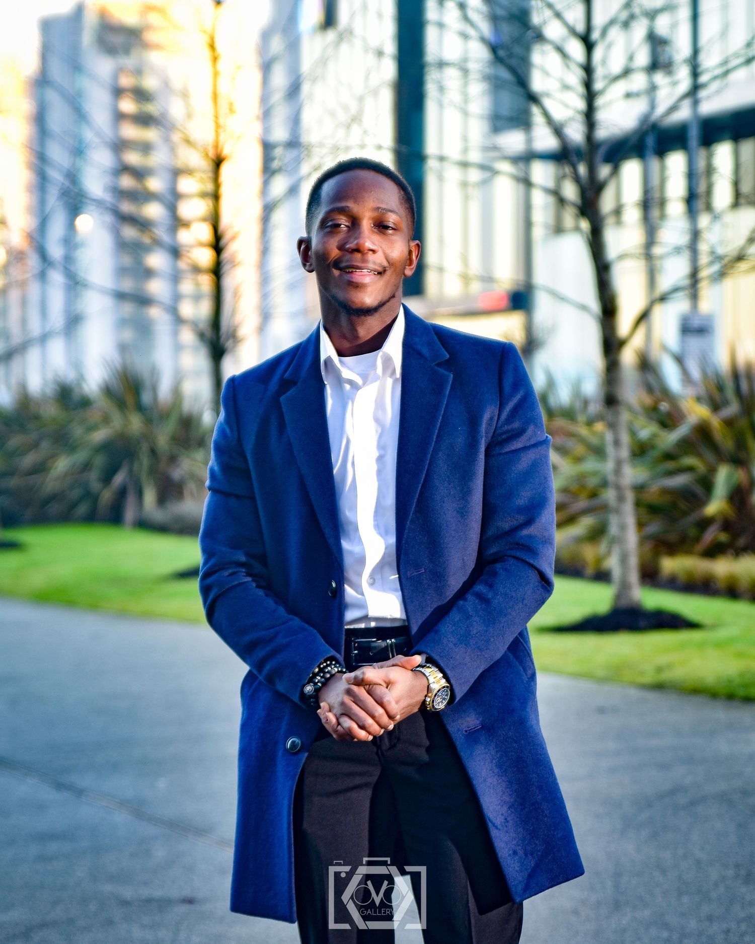 Stylish young man in a blue coat posing outdoors in an urban setting.