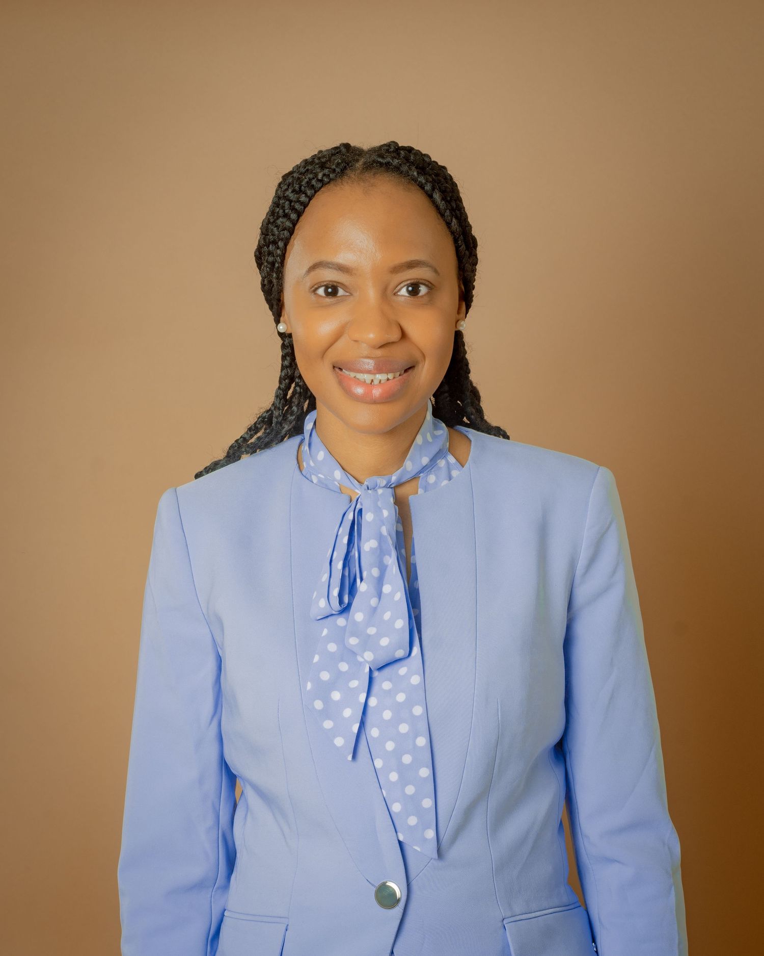 Professional woman smiling in a blue blazer and polka dot bow blouse.