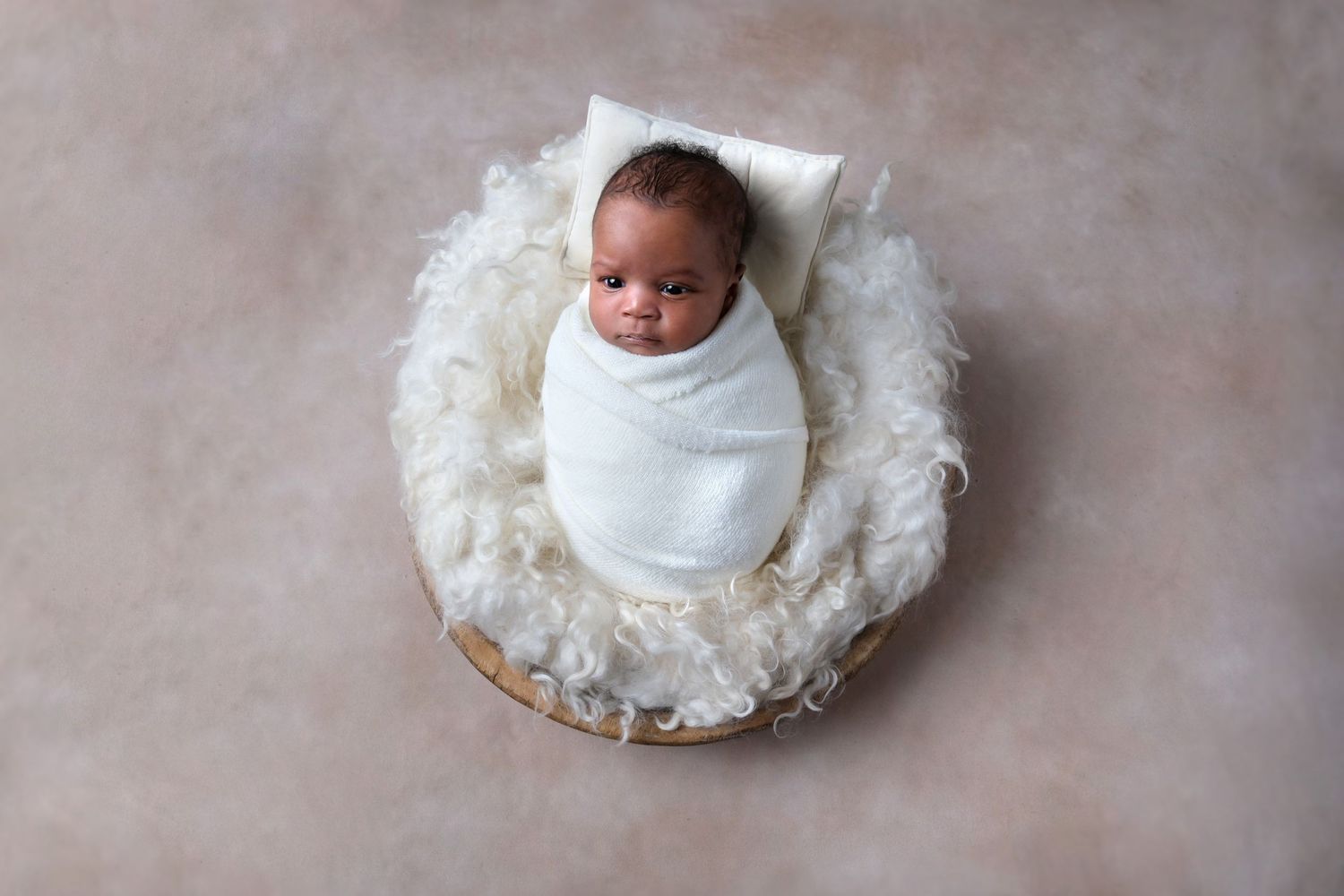 Newborn baby wrapped and posed in a bowl prop during newborn photography session