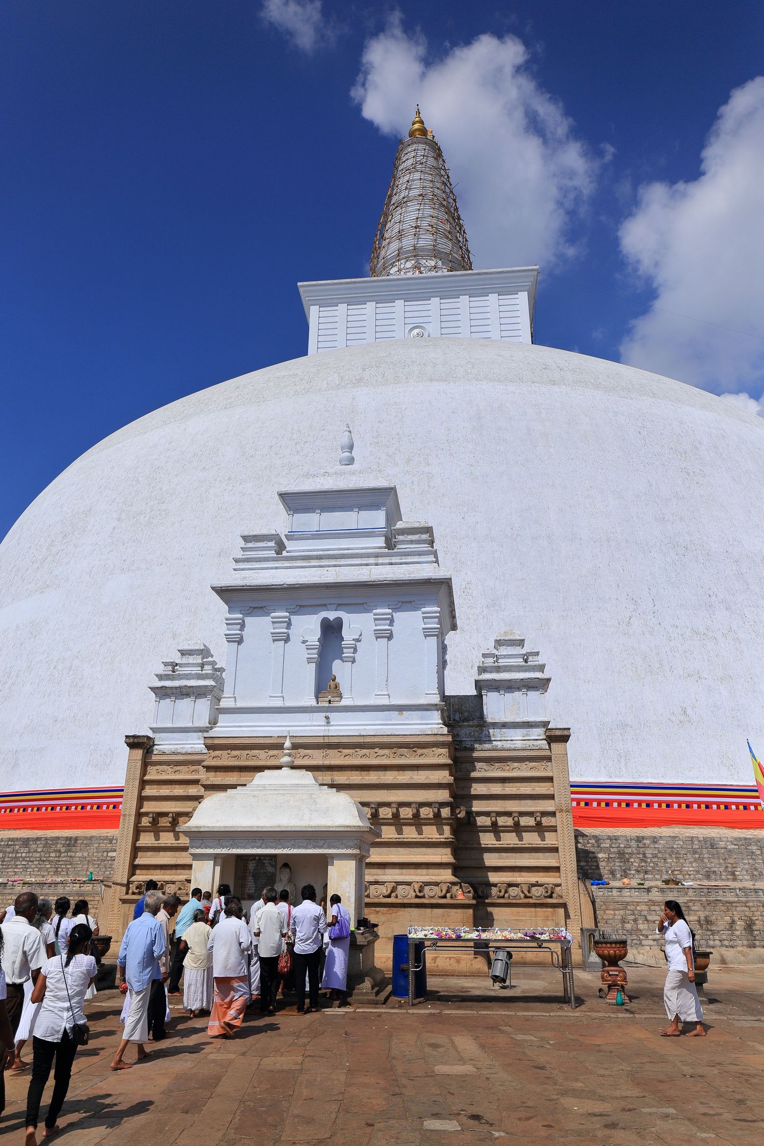 White Buddhist stupa temple entrance with ornate architectural details and visitors gathering.