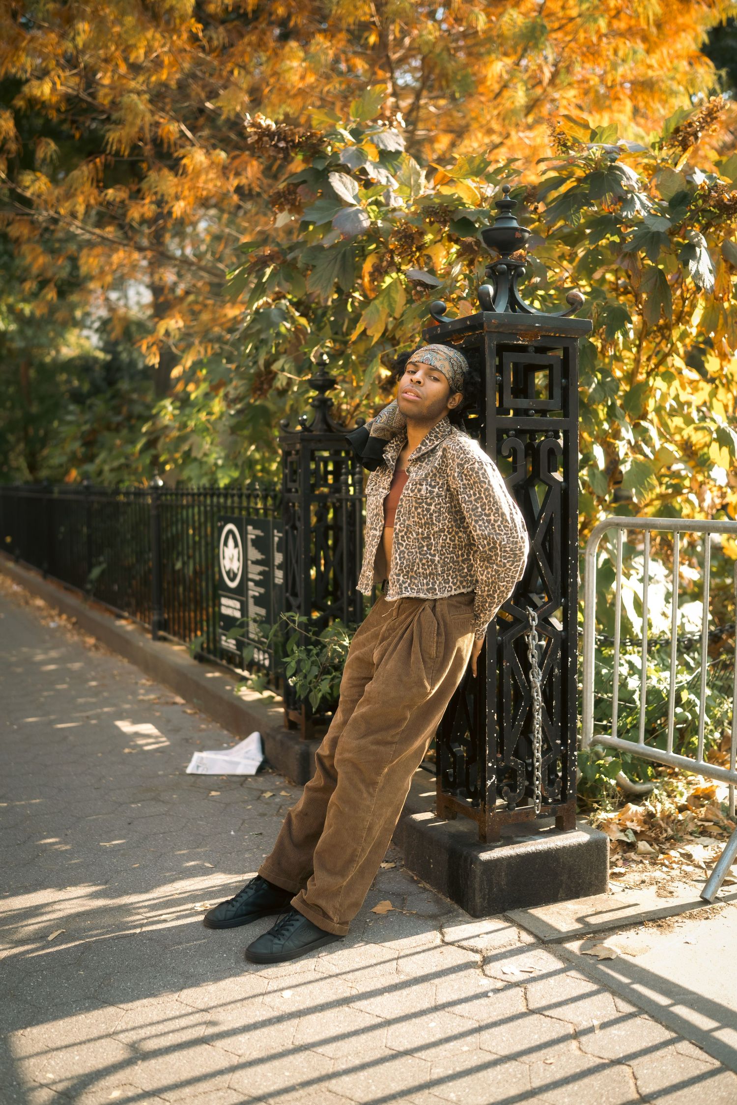 Fashion shoot with autumn foliage featuring casual wear against iron fence.