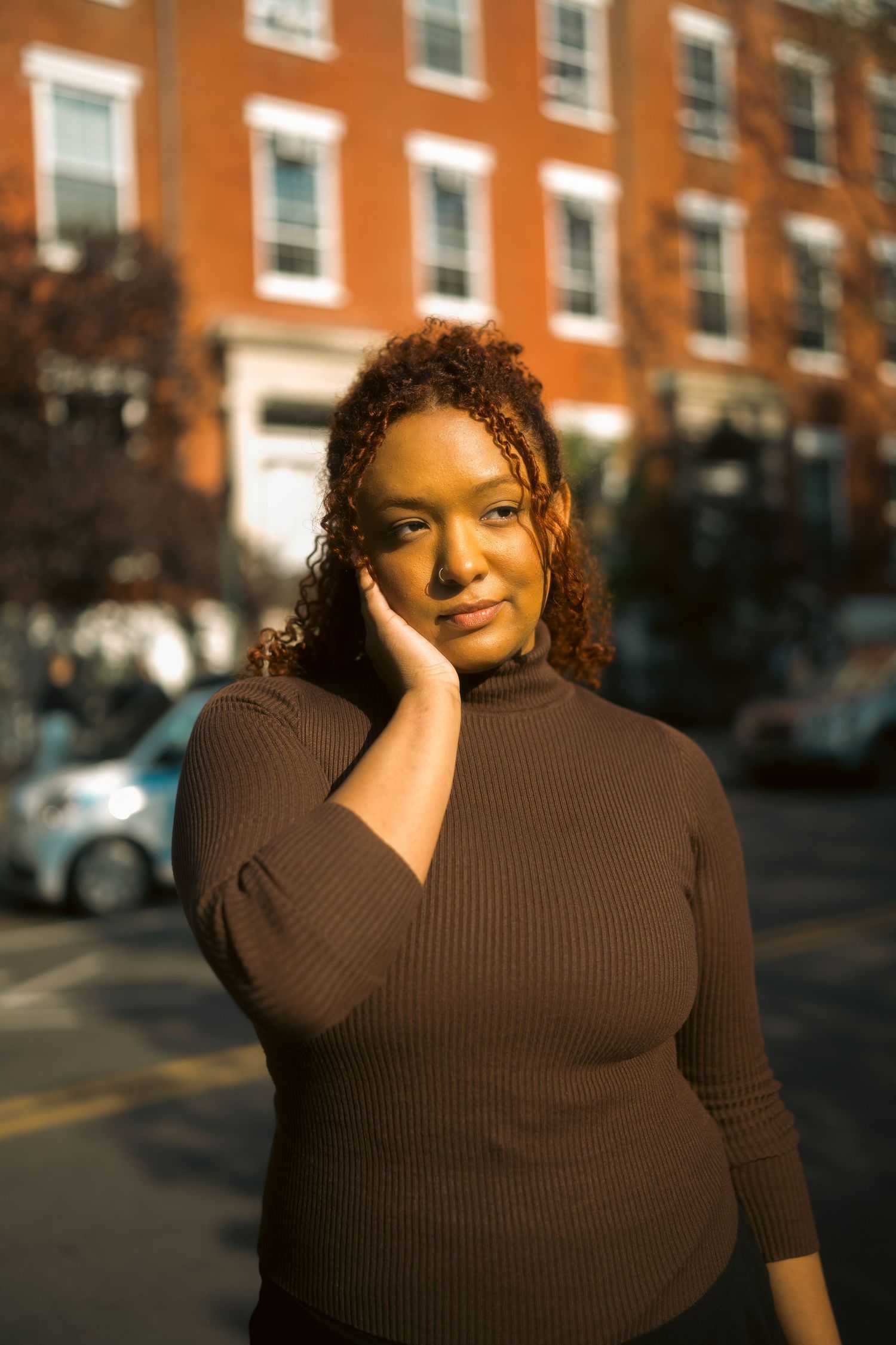 Portrait against brick building backdrop during golden hour lighting.