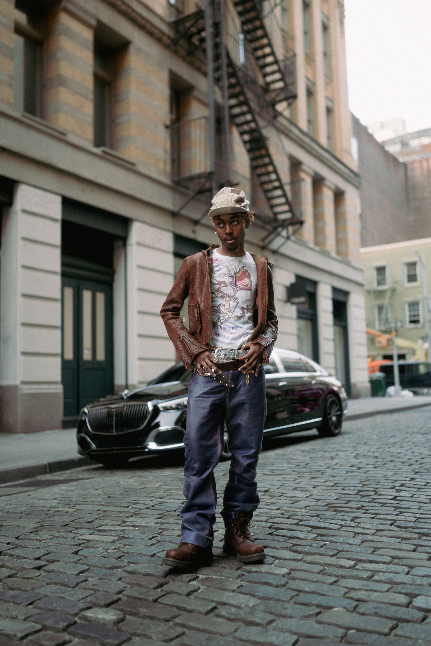 Street style fashion shot on cobblestone street with classic architecture and parked car.
