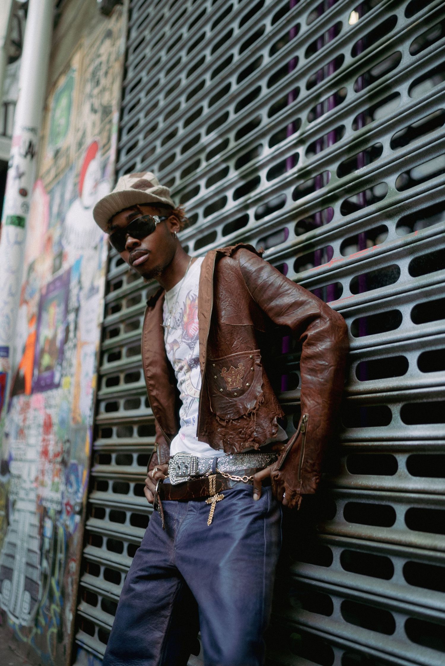 Urban fashion portrait against industrial metal grating with graffiti background.