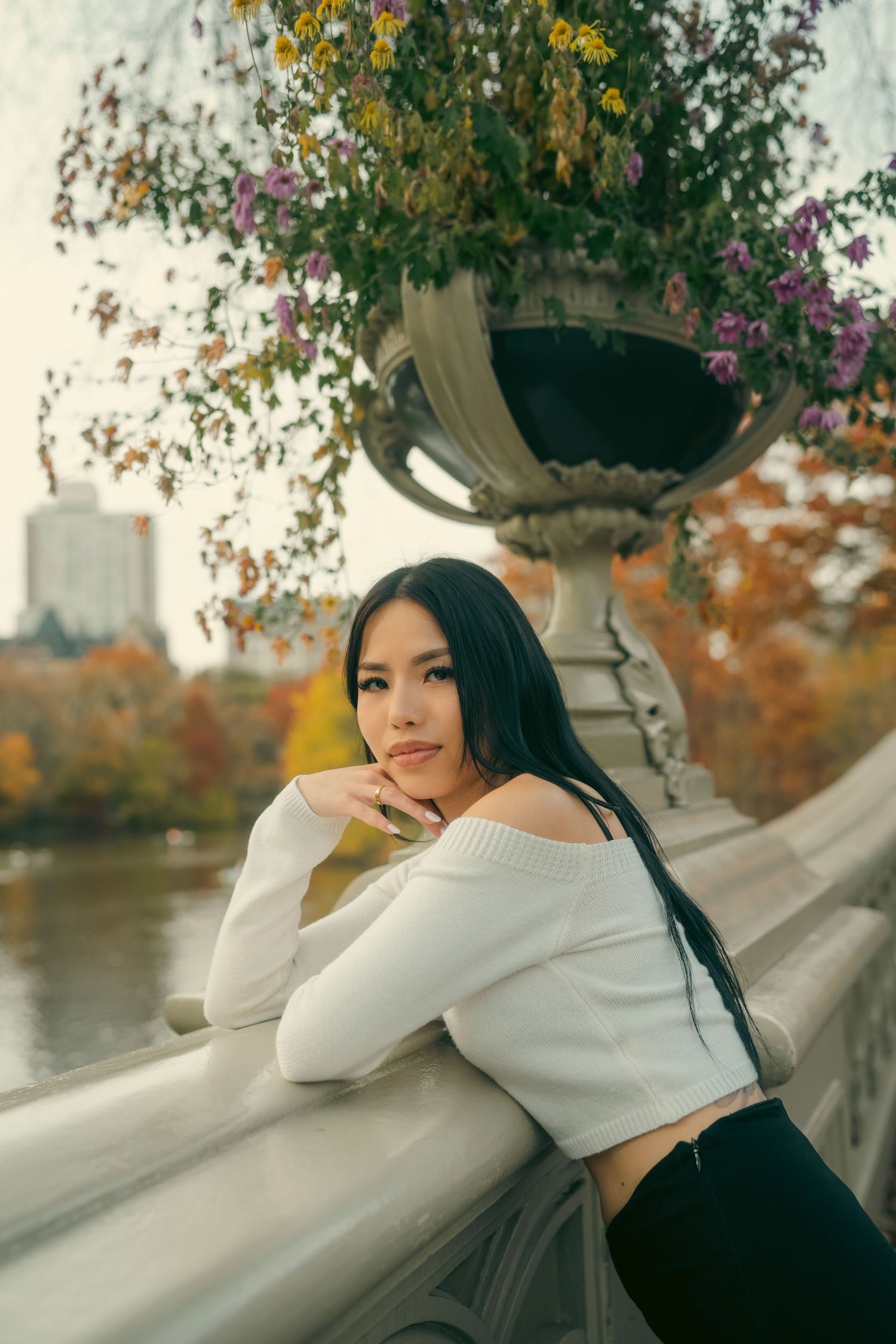 A series of autumn portraits showing someone in a white sweater sitting by a waterfront with colorful fall foliage.