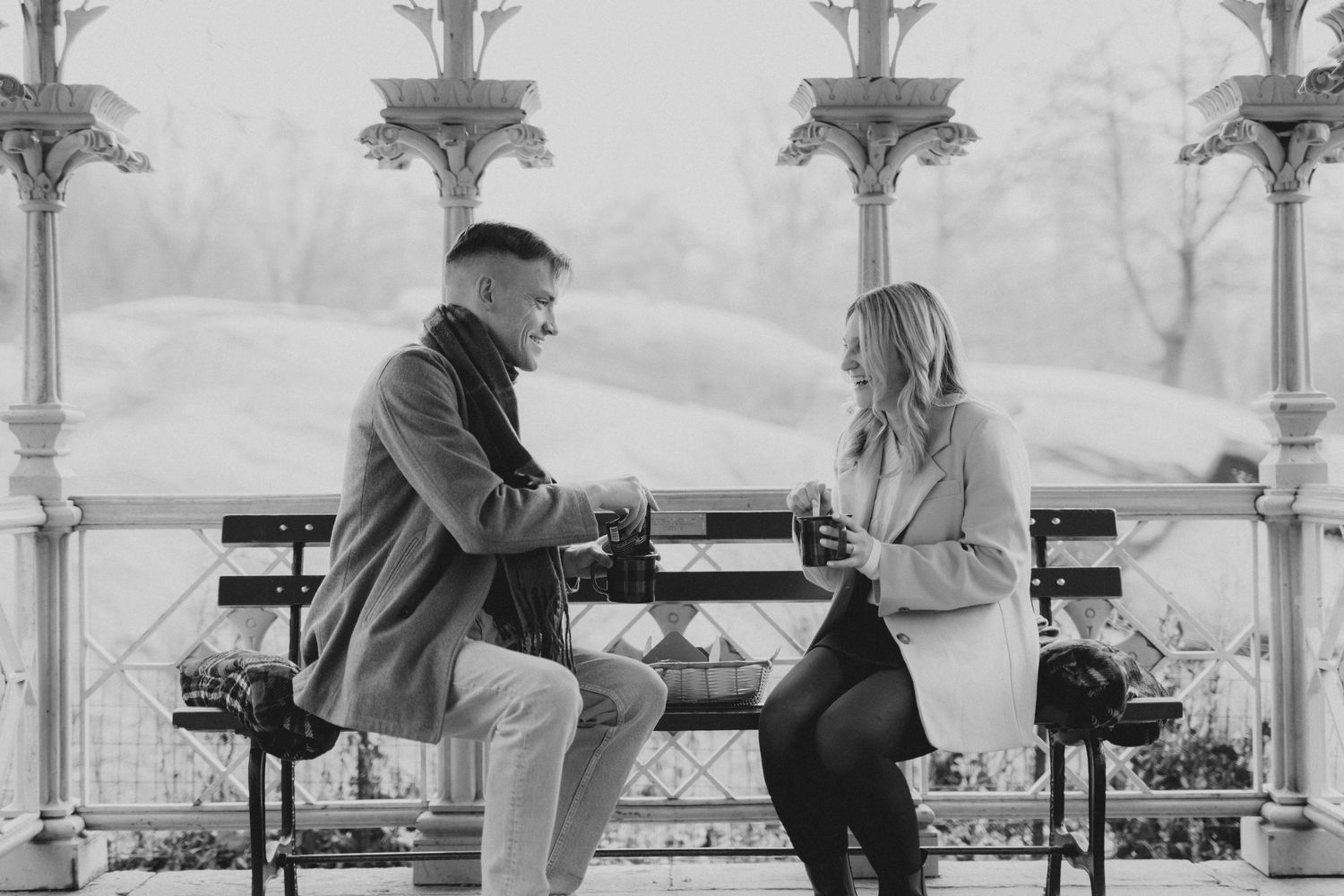 Black and white photo of people sitting on ornate benches in a garden setting.