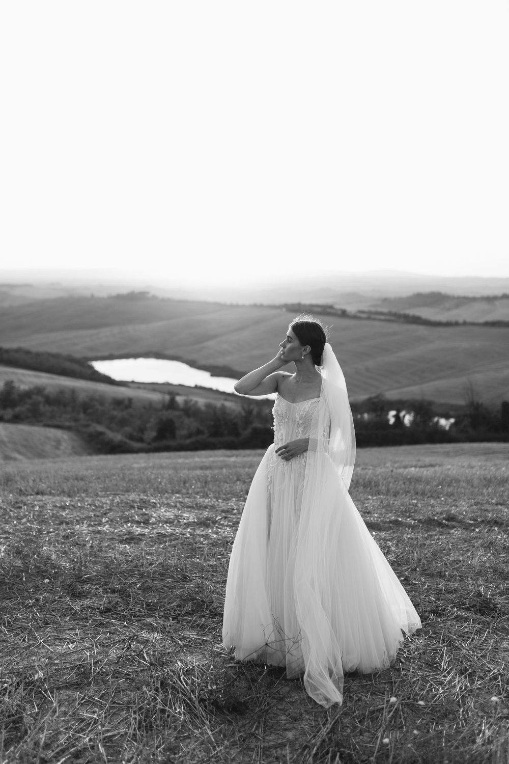 Ethereal black and white bridal portrait showing flowing dress and veil against scenic countryside.