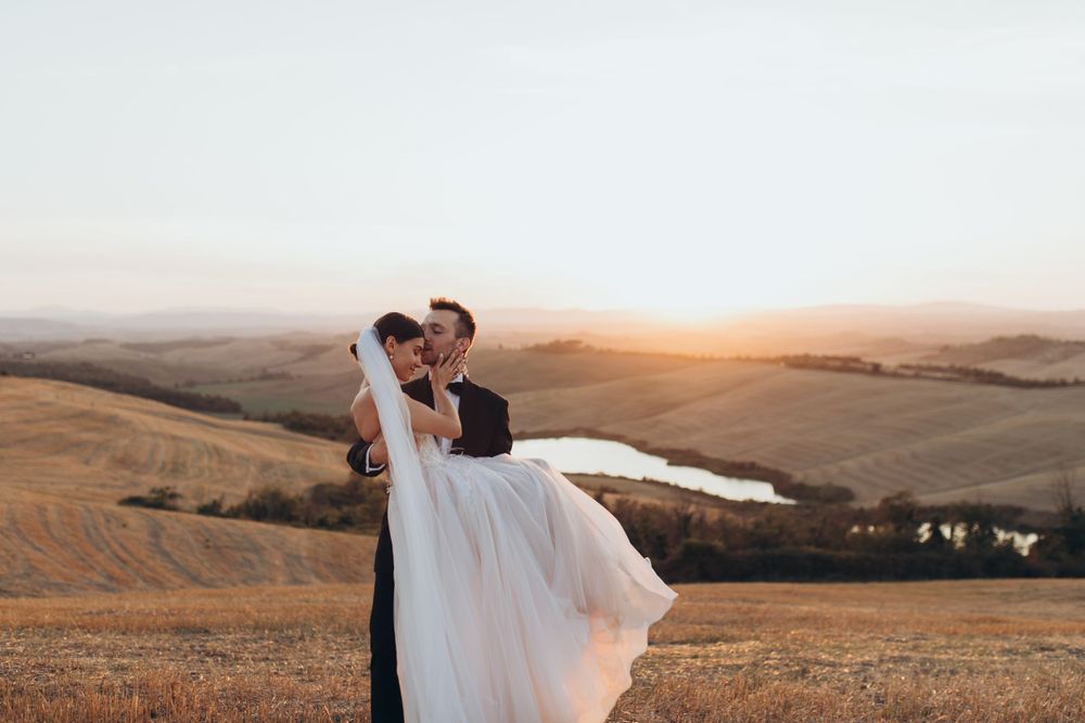 A sunset wedding portrait features a romantic dance pose overlooking golden hills and a lake.