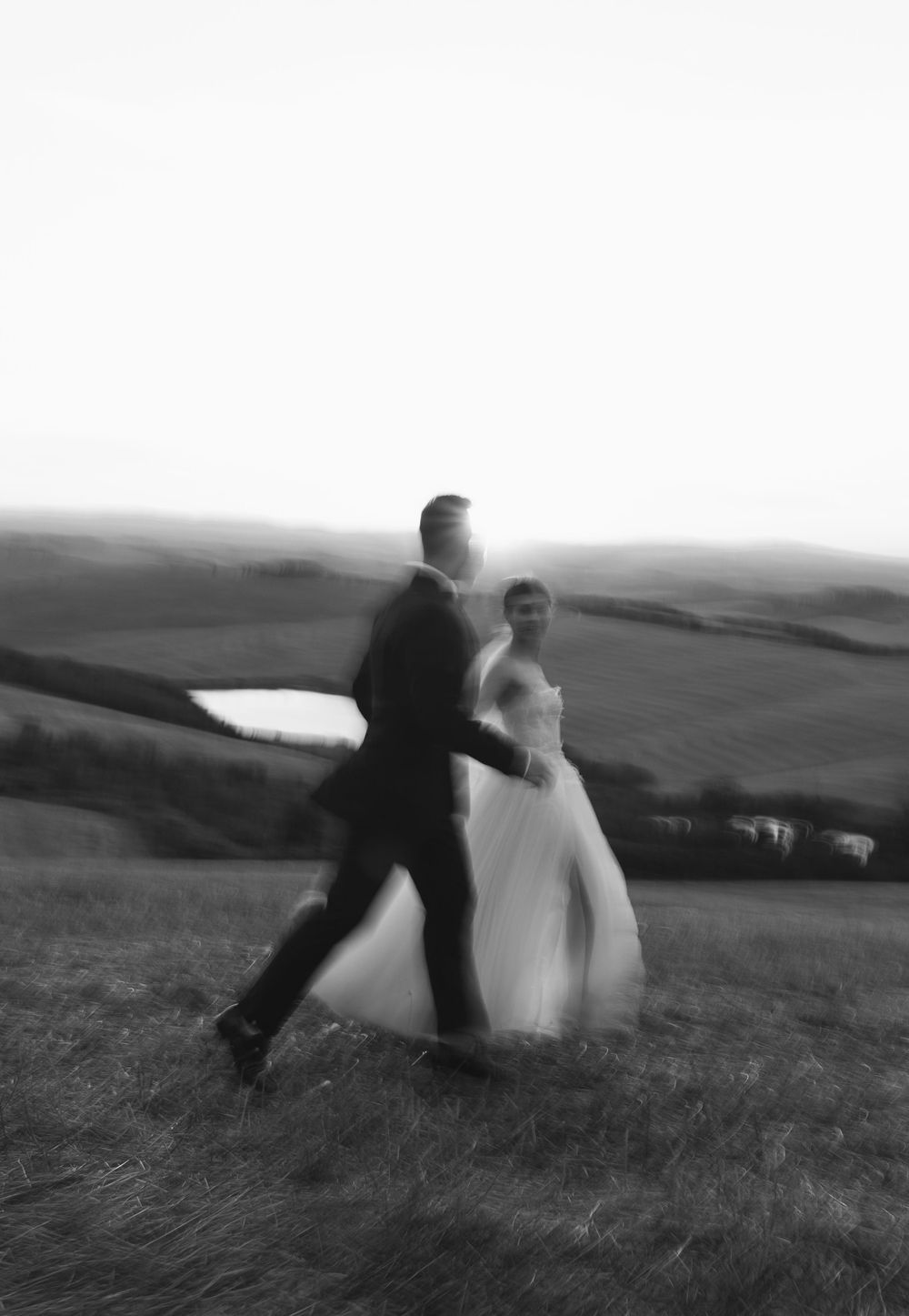 Black and white photo of a couple dancing on a scenic hilltop.