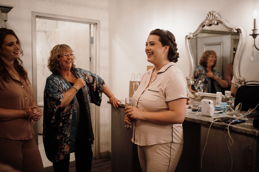 Bride smiling and celebrating with family members during wedding morning getting ready preparations.
