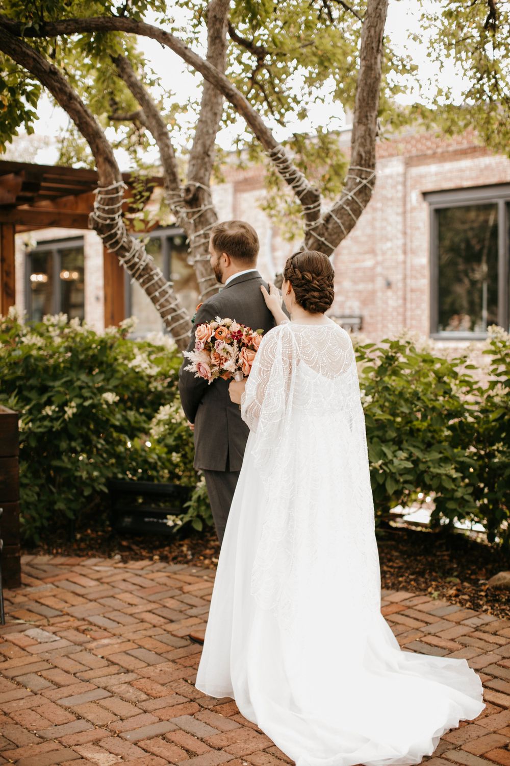 Bride and groom share a tender moment together during first look on brick pathway.