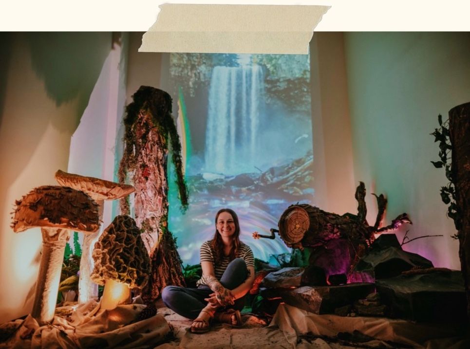 queer nonbinary white artist and photographer kimberly marie kimble sits in art installation they made portland oregon