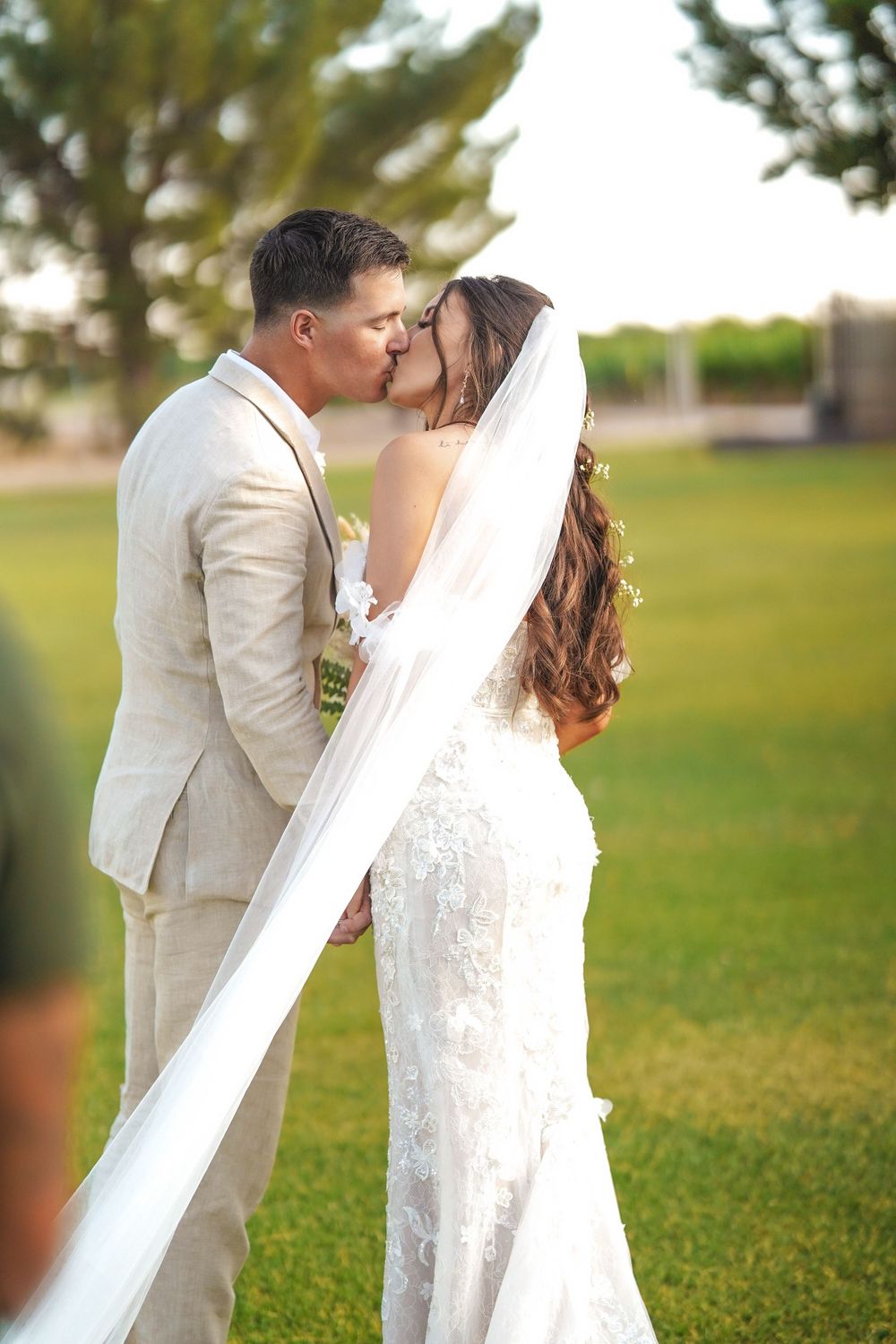 A romantic moment captured between newlyweds with a flowing white veil in a garden setting.