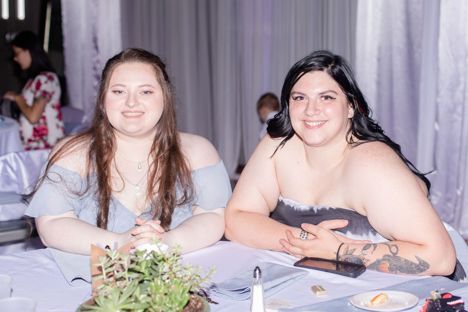 Wedding reception guests seated at tables with white linens and floral centerpieces.