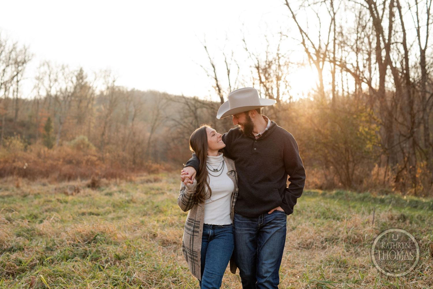 A joyful couple shares a tender moment in an autumn field at sunset.