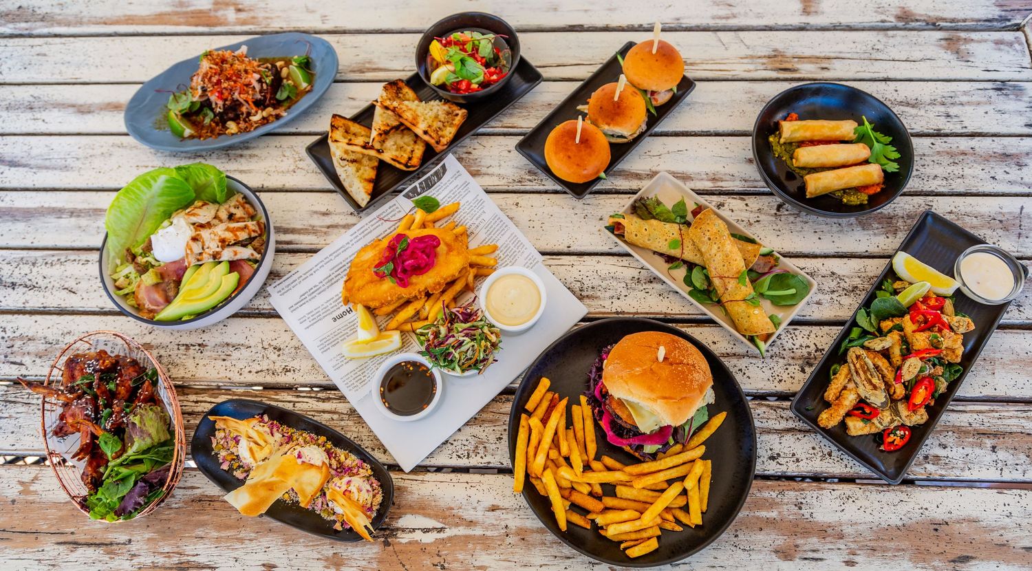 Overhead view of various gourmet dishes served on wooden table.