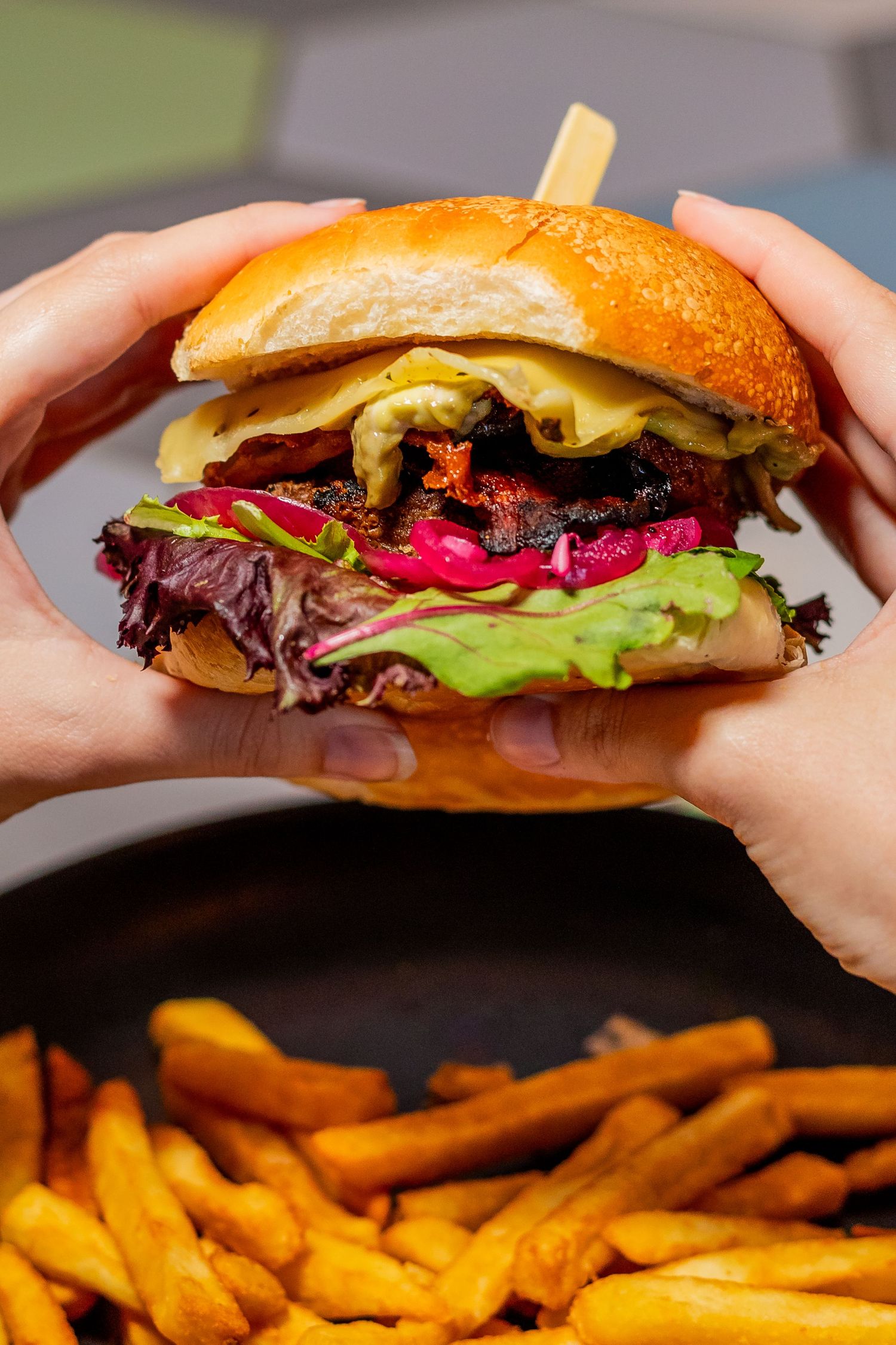 Juicy cheeseburger with lettuce, purple cabbage, and melted cheese on a brioche bun.