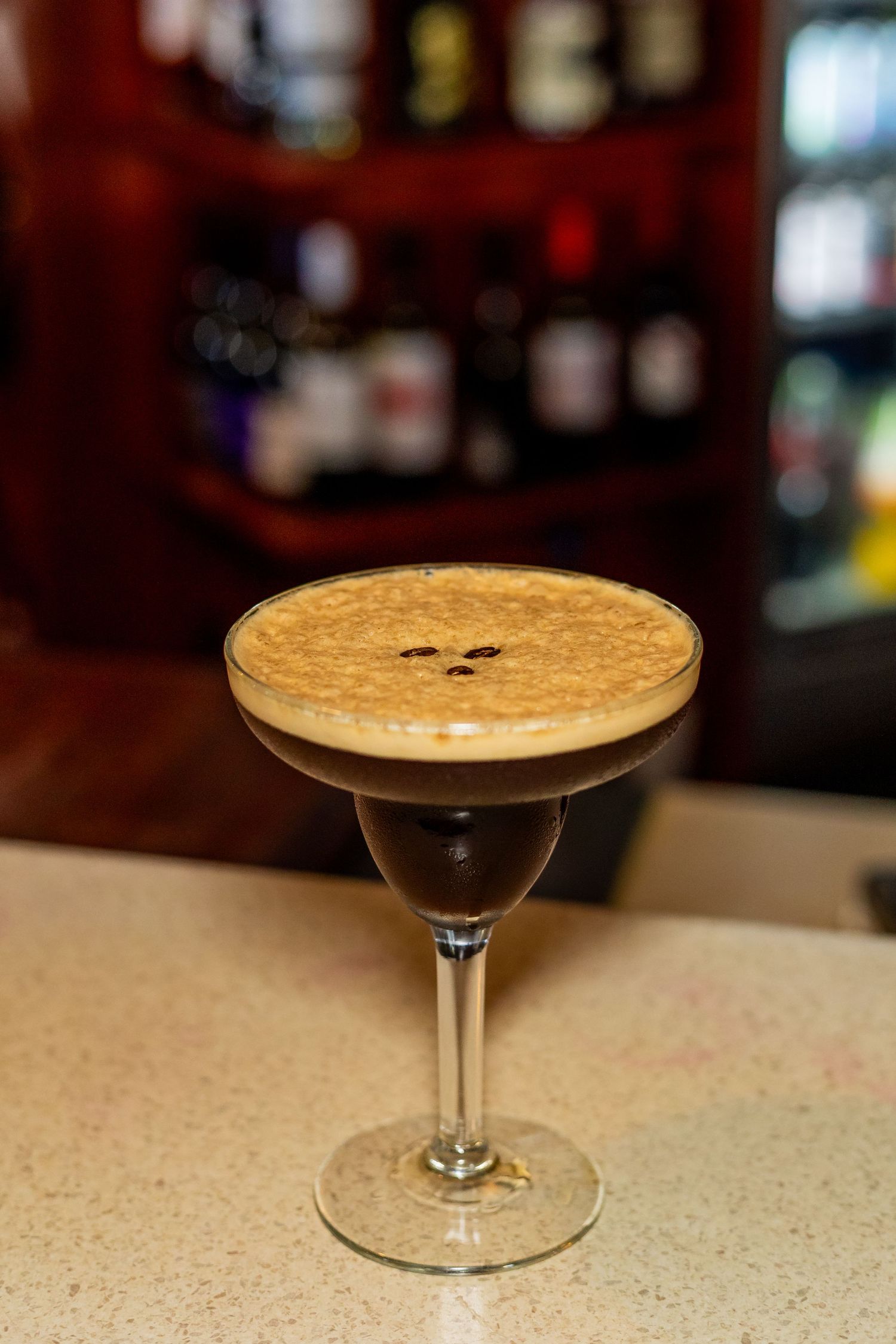 Espresso martini cocktail with creamy foam and coffee beans in a coupe glass.