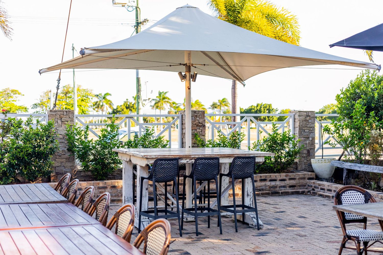 Outdoor dining area with white umbrella and bistro chairs on wooden deck.