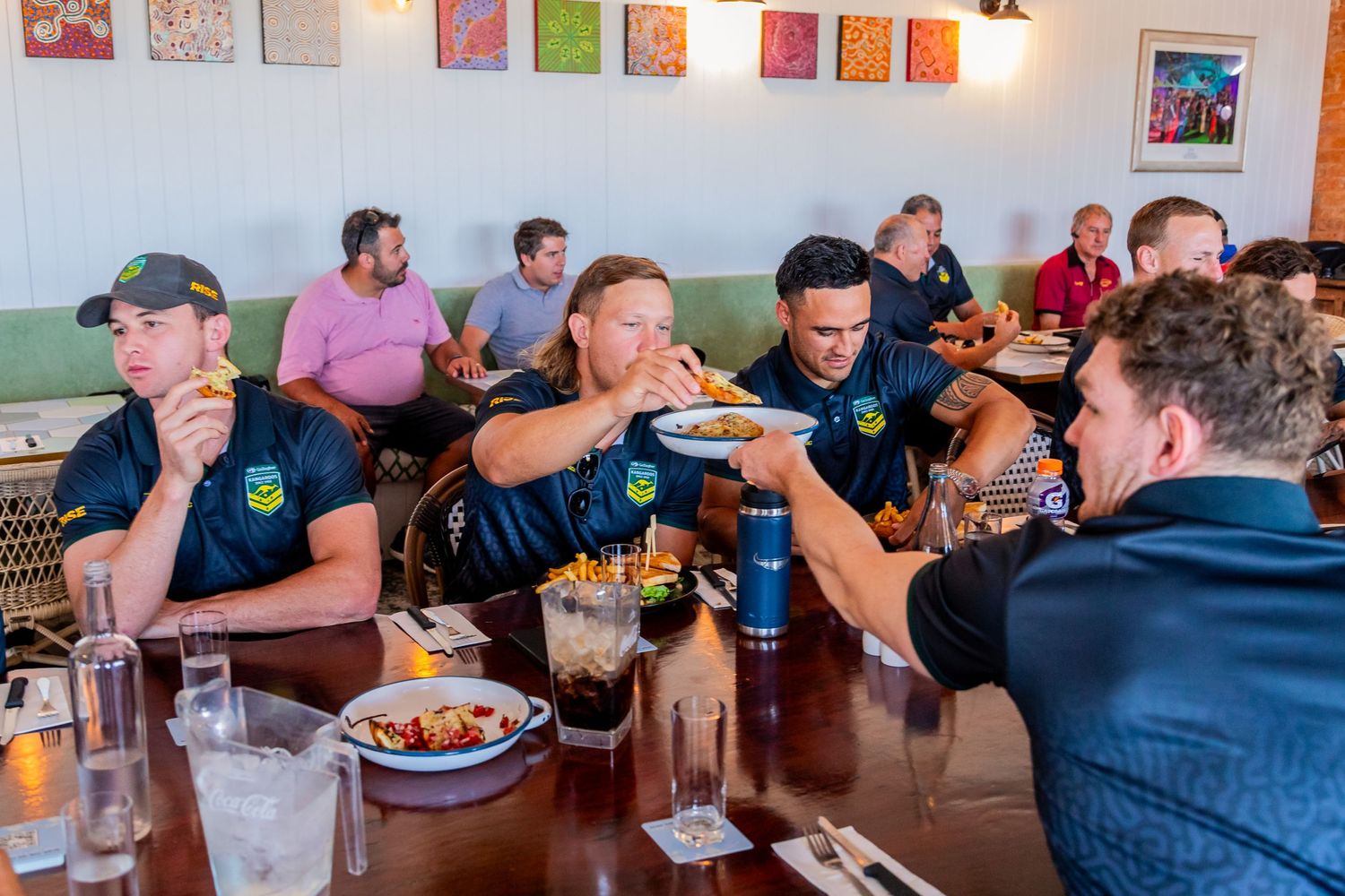 Restaurant dining room filled with guests enjoying meals at long tables.