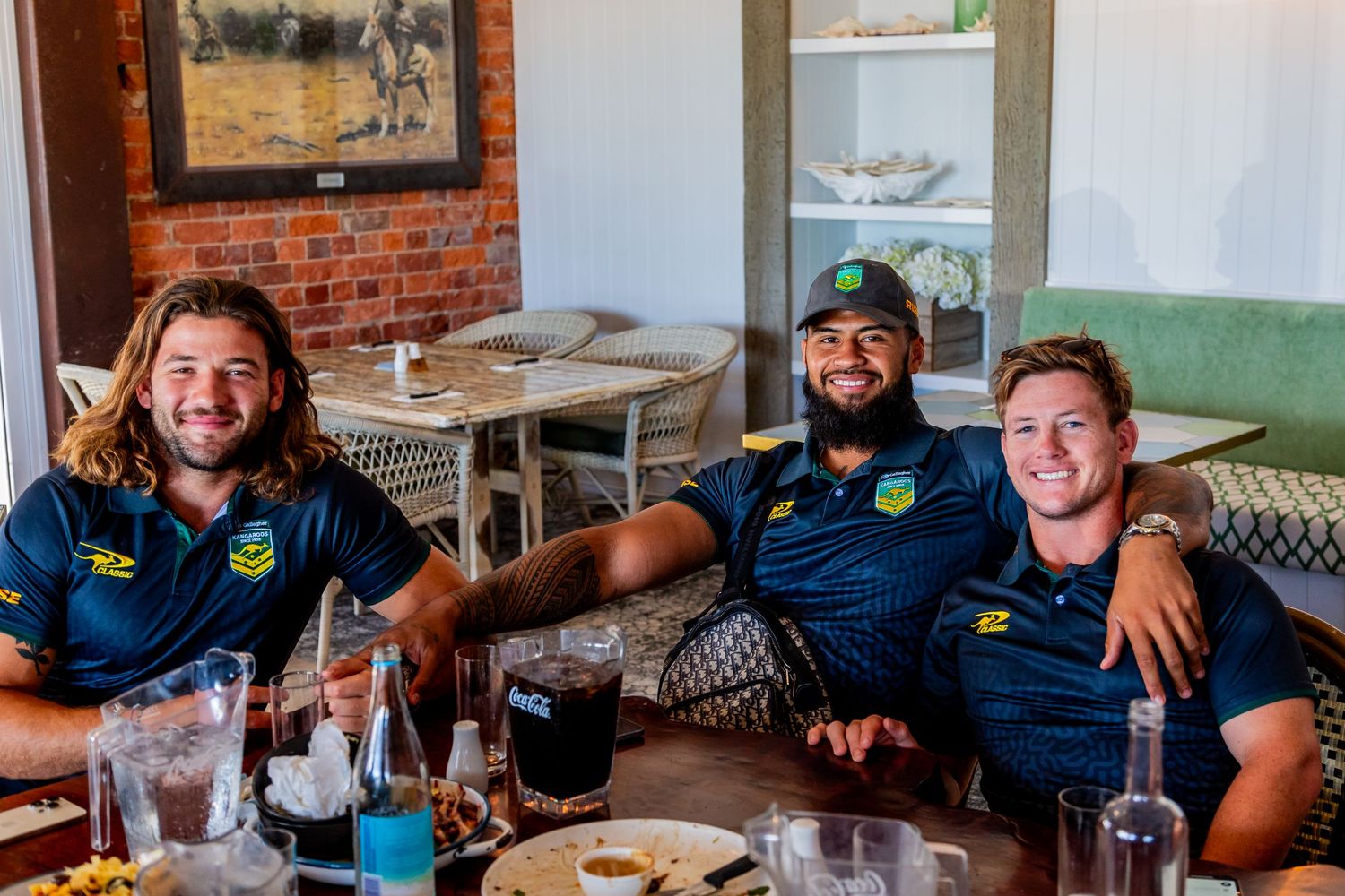 Three sports team members sharing a meal at a casual dining table.