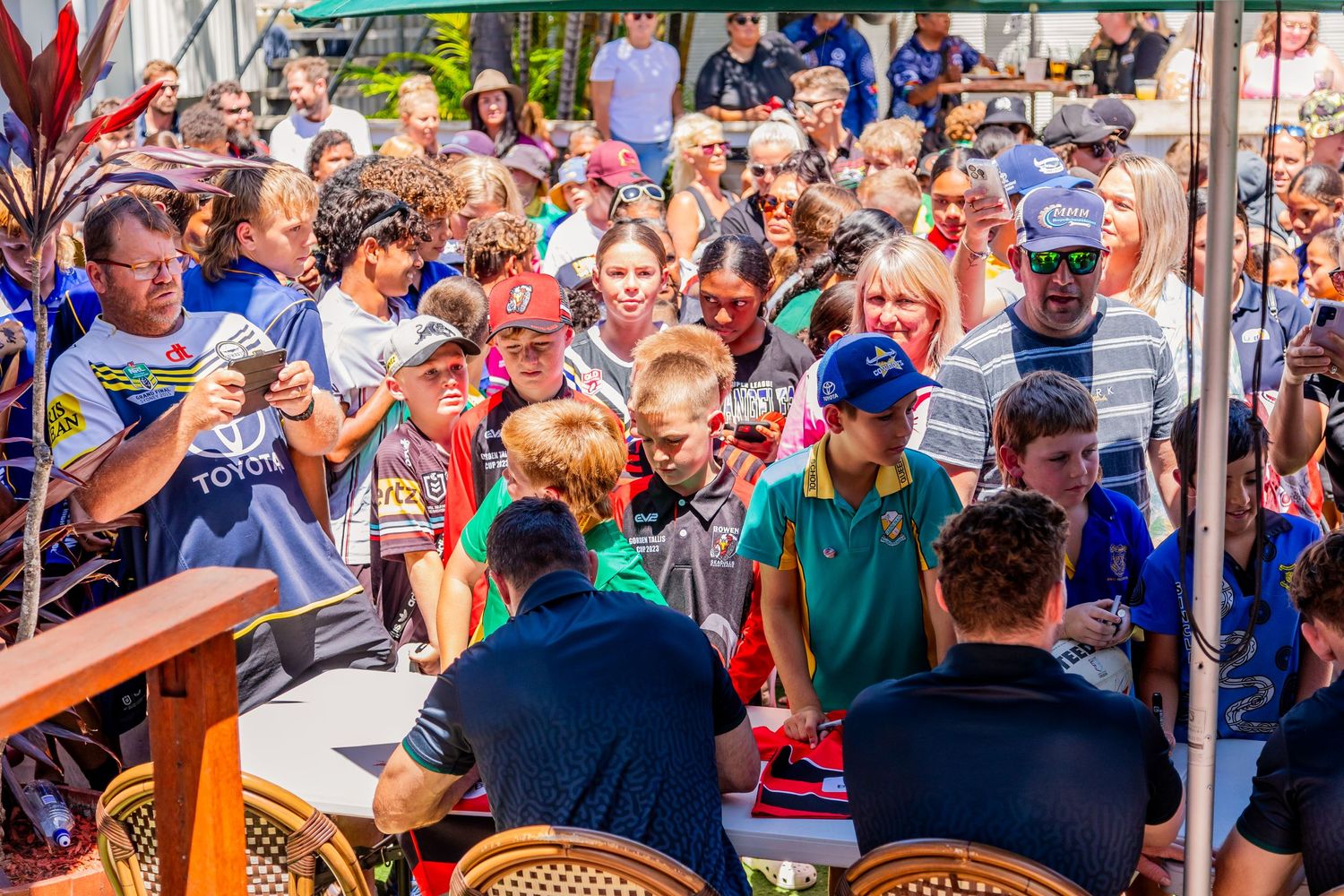 Crowd of sports fans gather around a table at an autograph signing event.