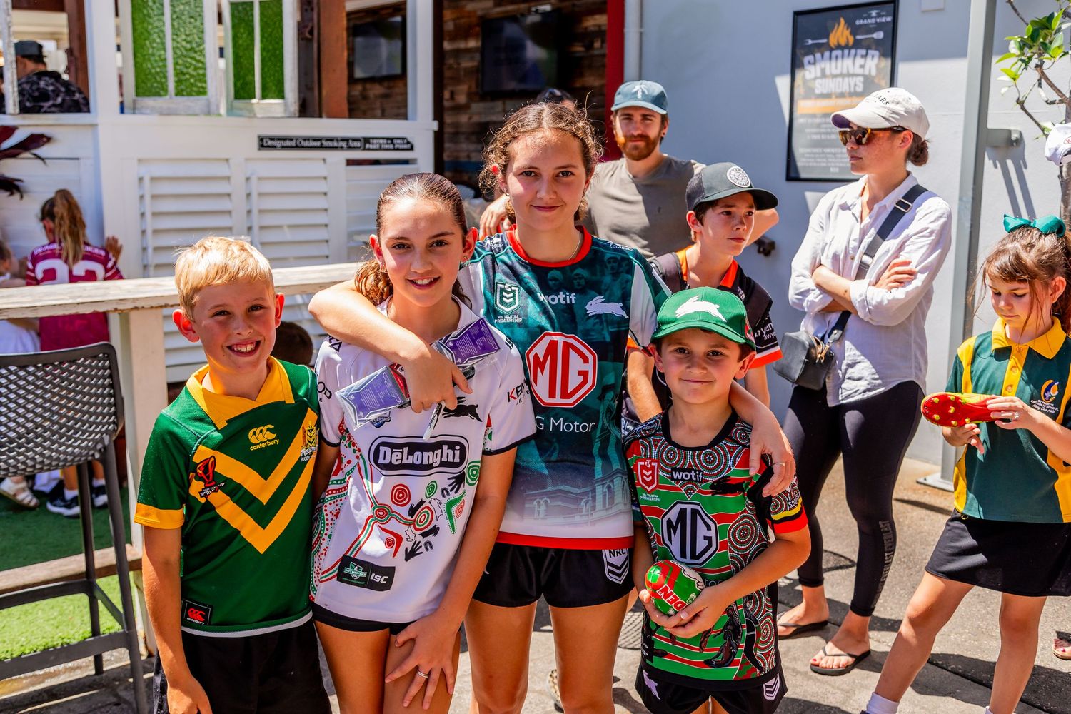 Young sports fans in team jerseys pose together at a community event.