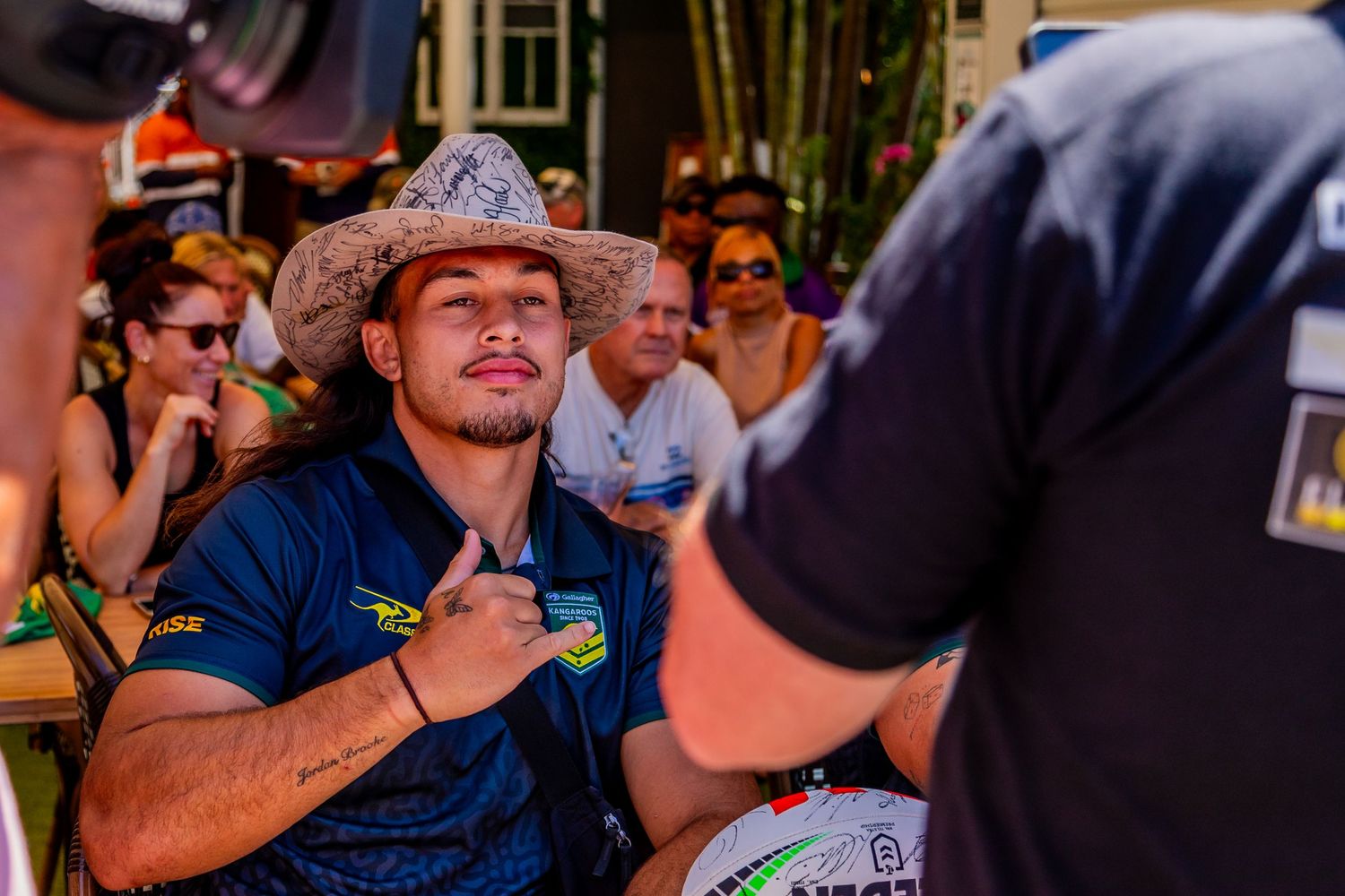 Fan wearing a cowboy hat interacts with someone at a sports signing event.