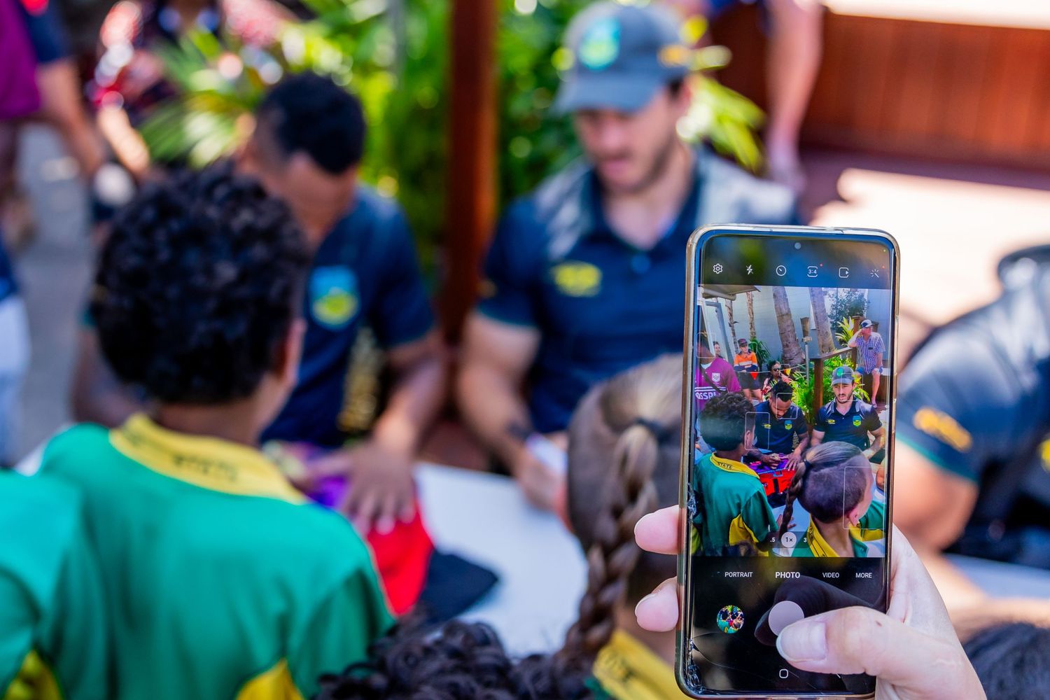 Someone taking a photo of athletes signing autographs with their smartphone.