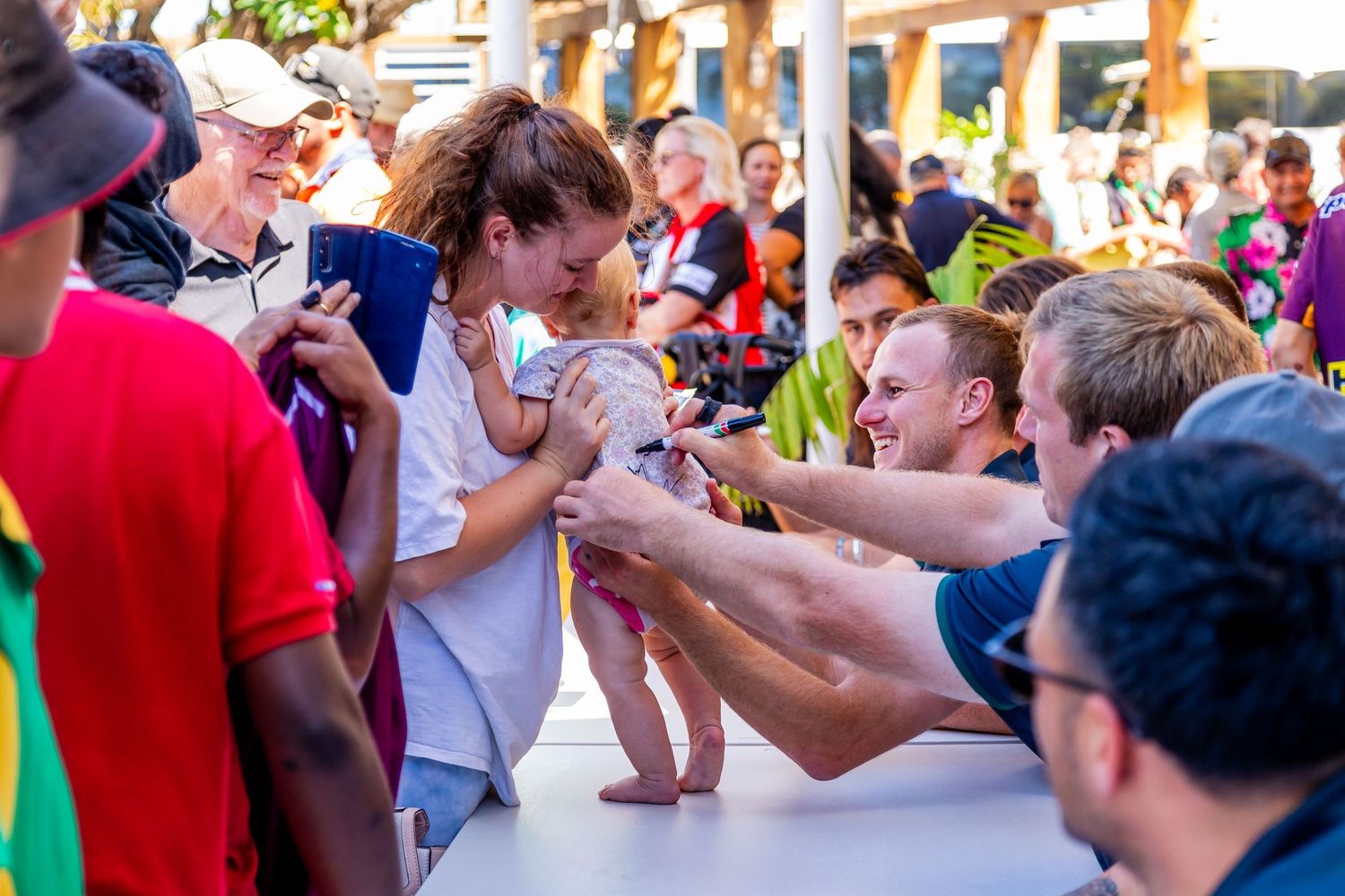 Excited fans reach out for autographs at a sports signing event.