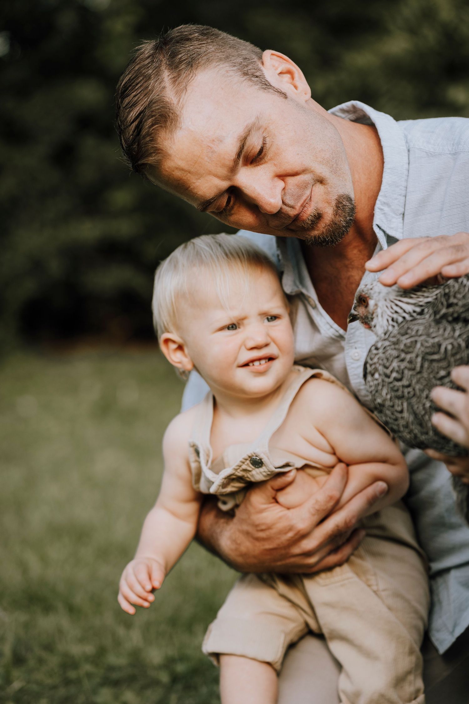 A tender moment shared while holding a speckled chicken in the garden.