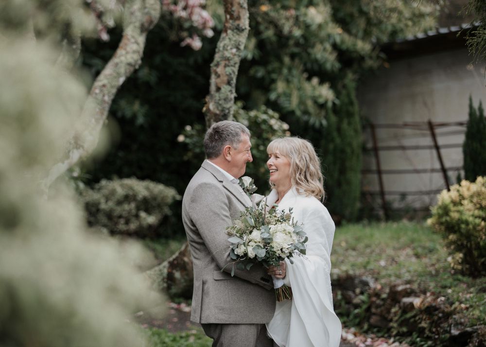 Bride and Groom stand under magnolia tree in St Elizabeth's House Plympton