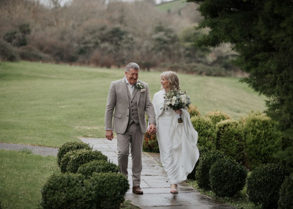 Bride and Groom walk through gardens at St Elizabeth's House in Plympton