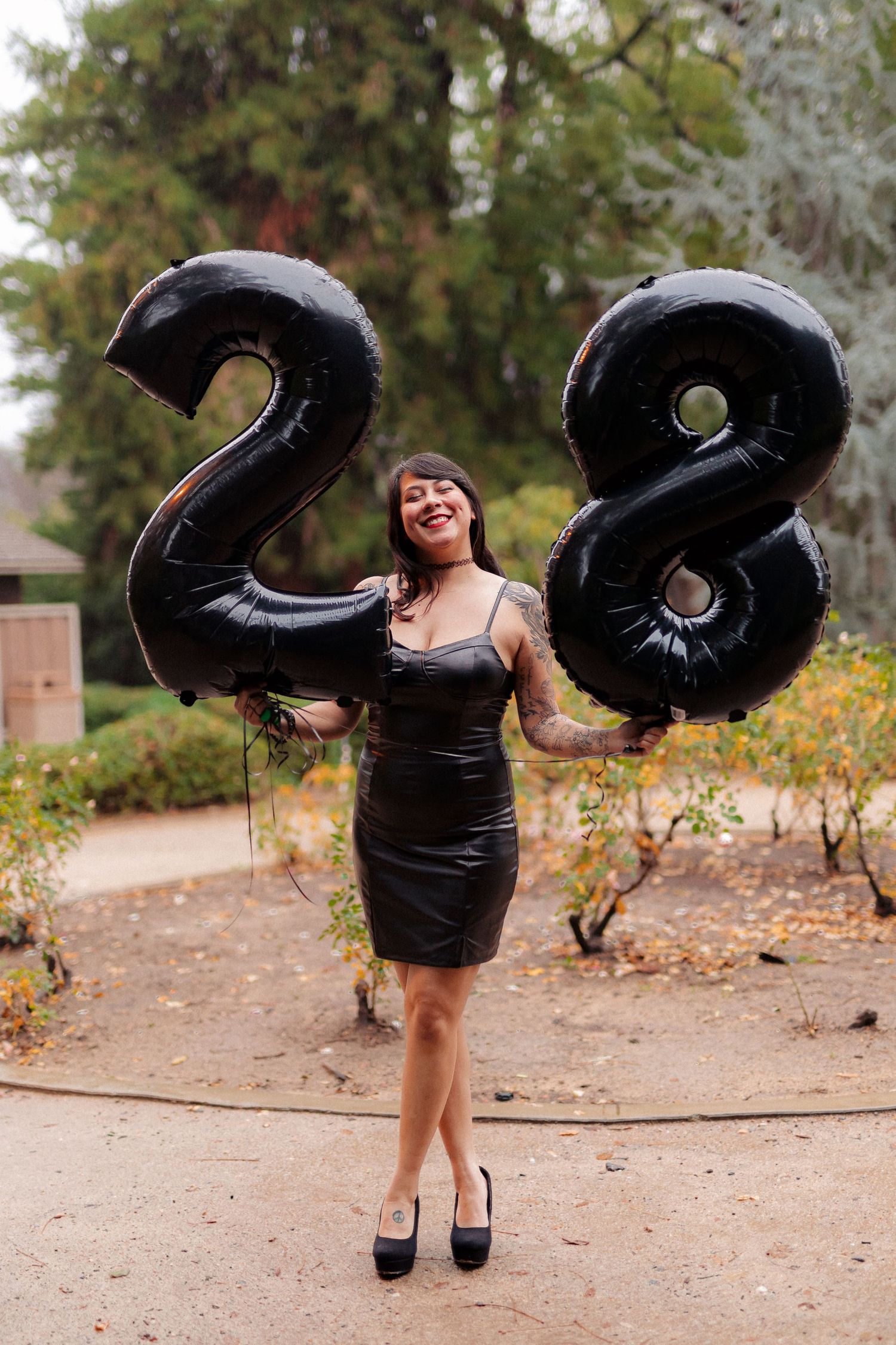 A celebratory scene with large black number 28 balloons and a person in a black dress.