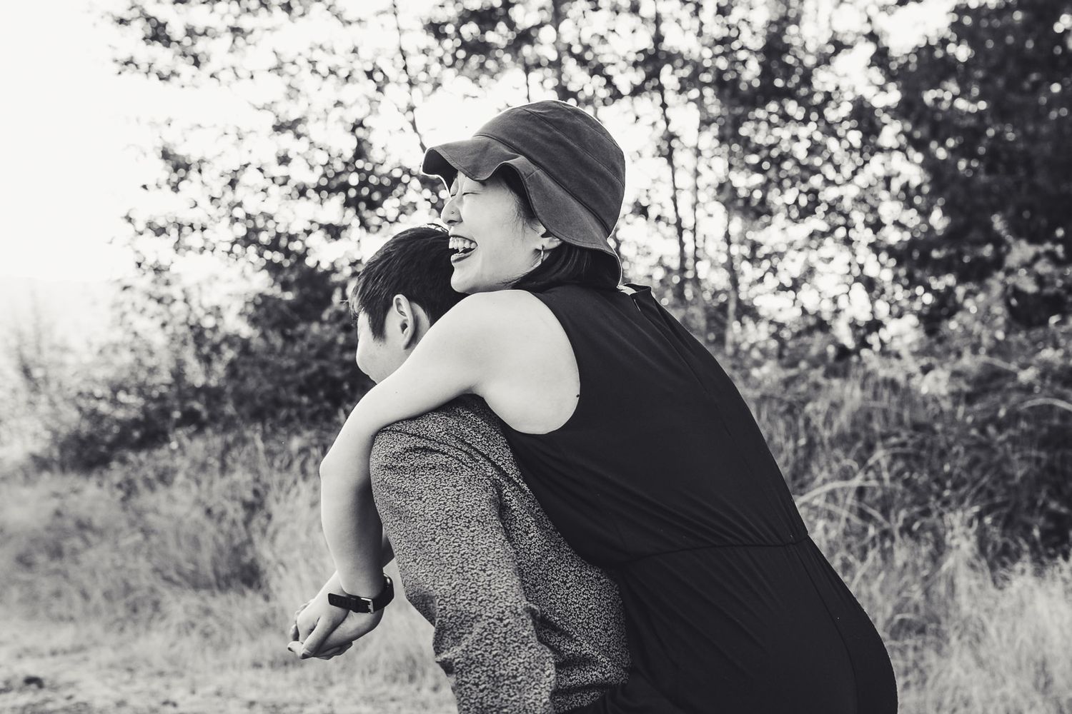 Black and white photo of sister laughing on brothers back in Issaquah Highlands by Redmond Family Photographer