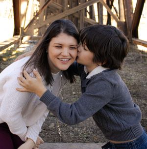 Sweet moment of affection shared between two people outdoors near a rustic structure.