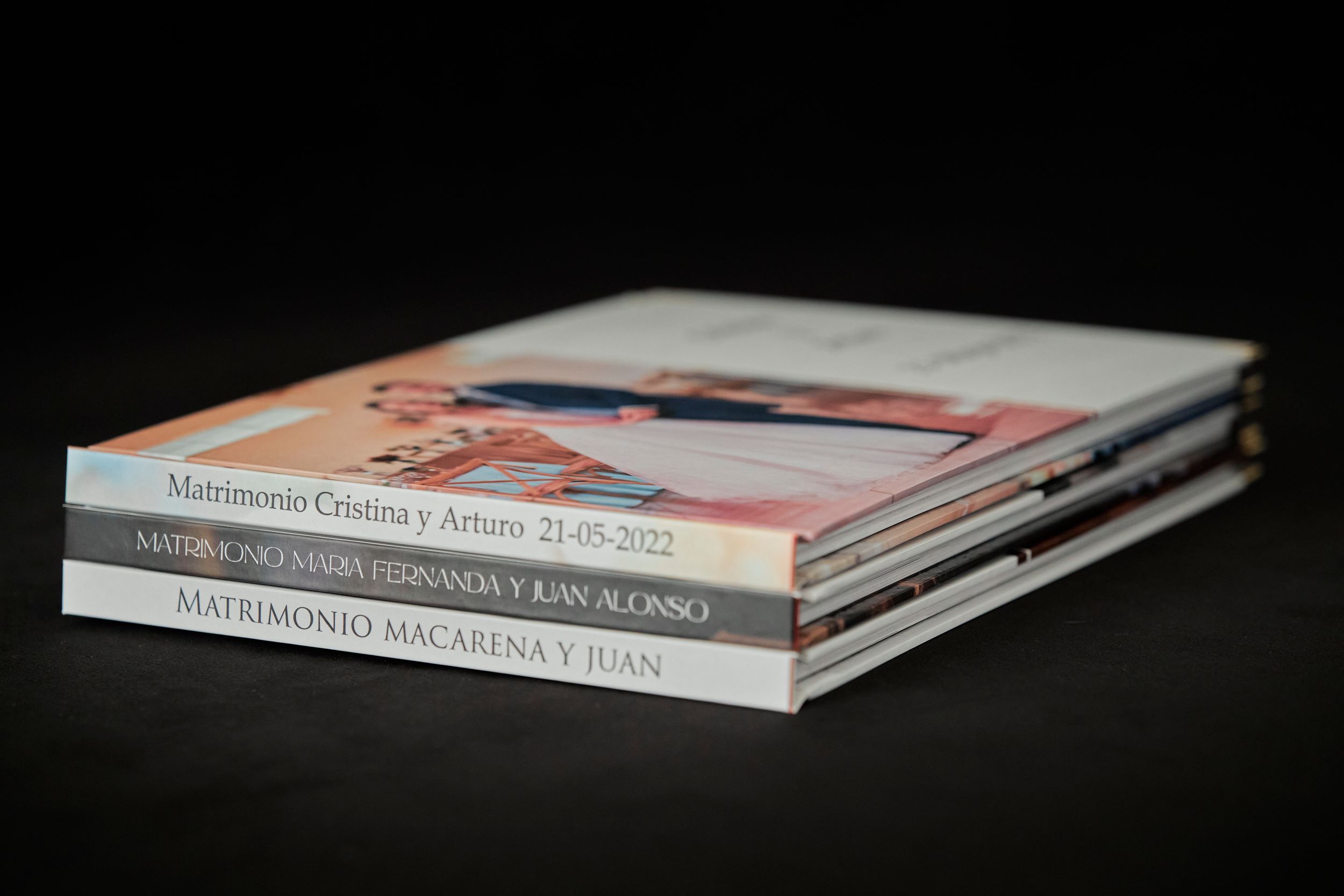 Stack of wedding photo albums with spine text visible against dark background.