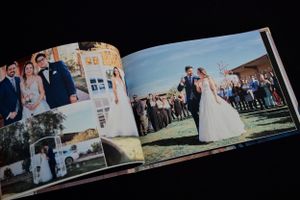 Wedding photo album pages displaying outdoor ceremony and group shots at a venue.