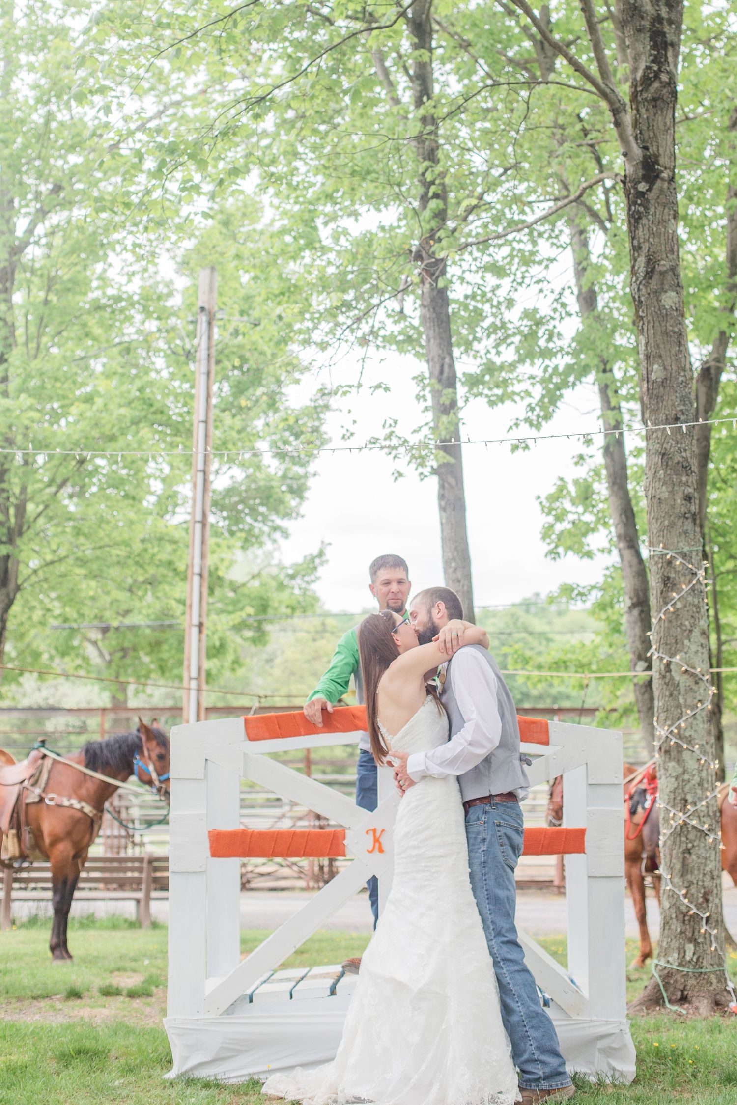 Couple shares romantic moments outdoors under green trees with white and orange decor.