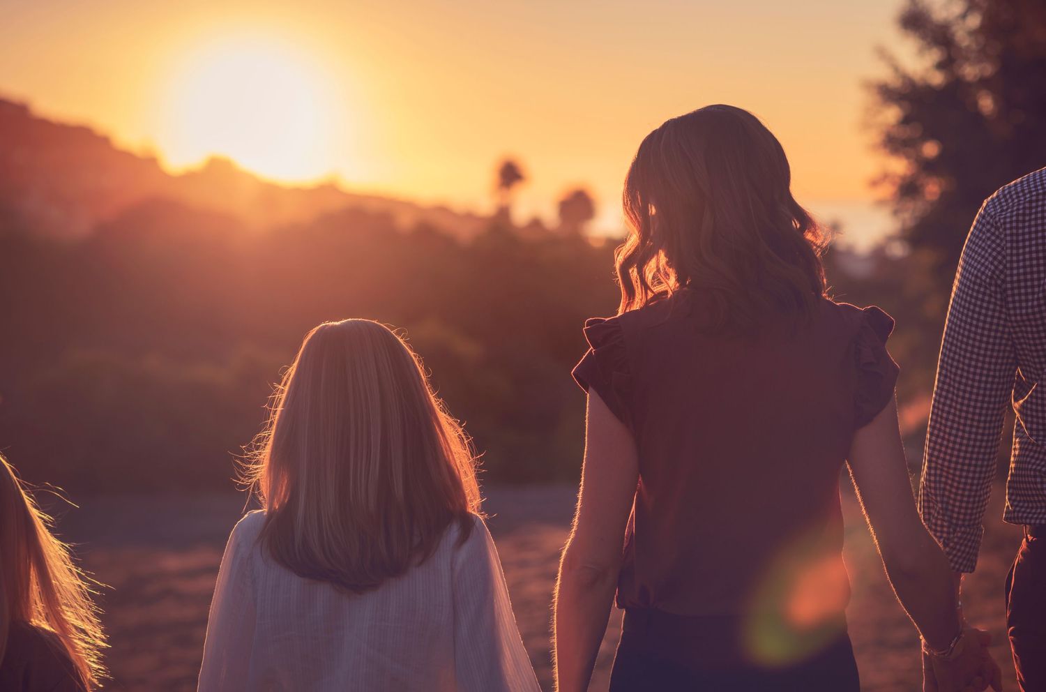 Three figures walking together at sunset with golden light streaming through.