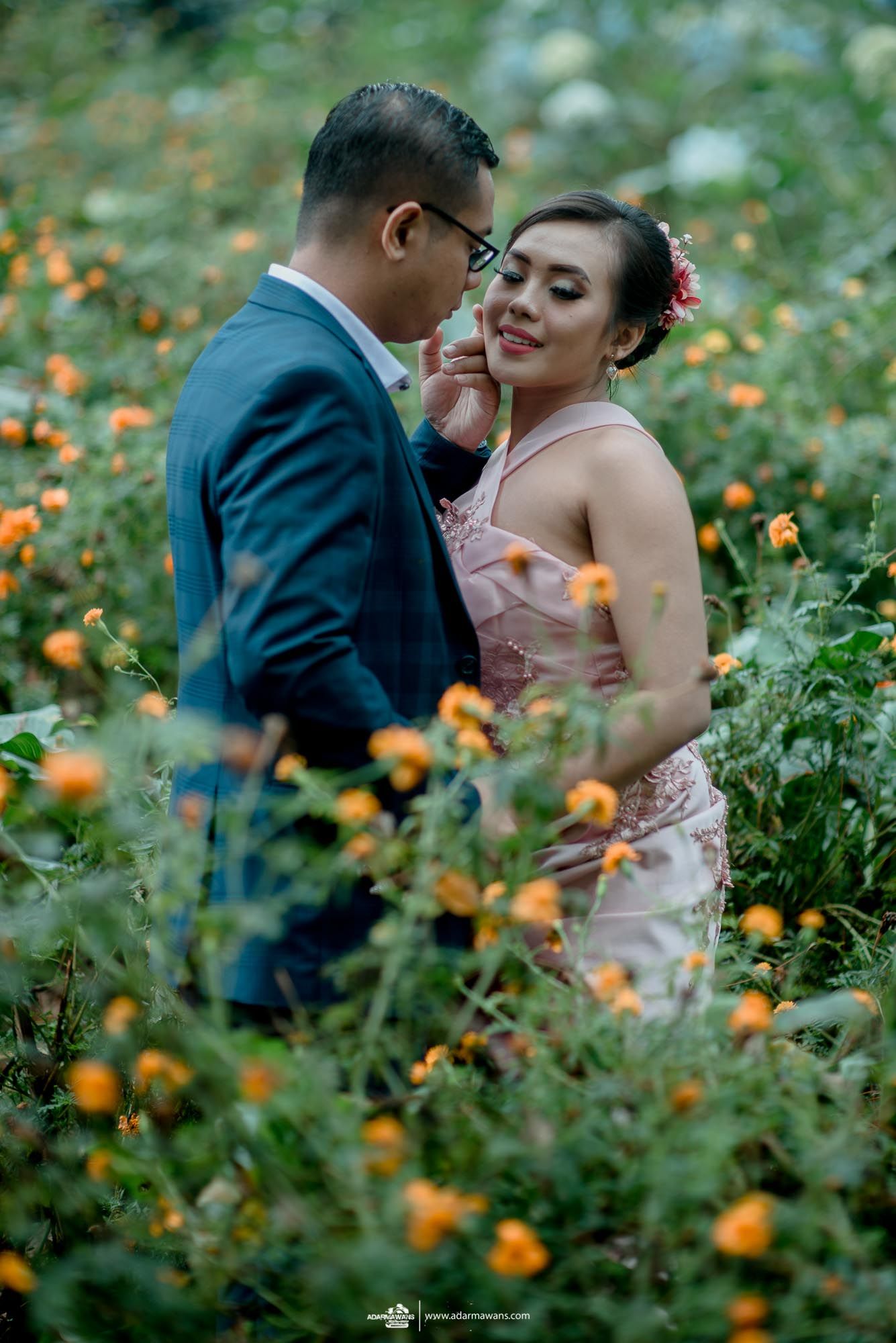 Intimate moment captured in garden with orange flowers blooming in foreground.